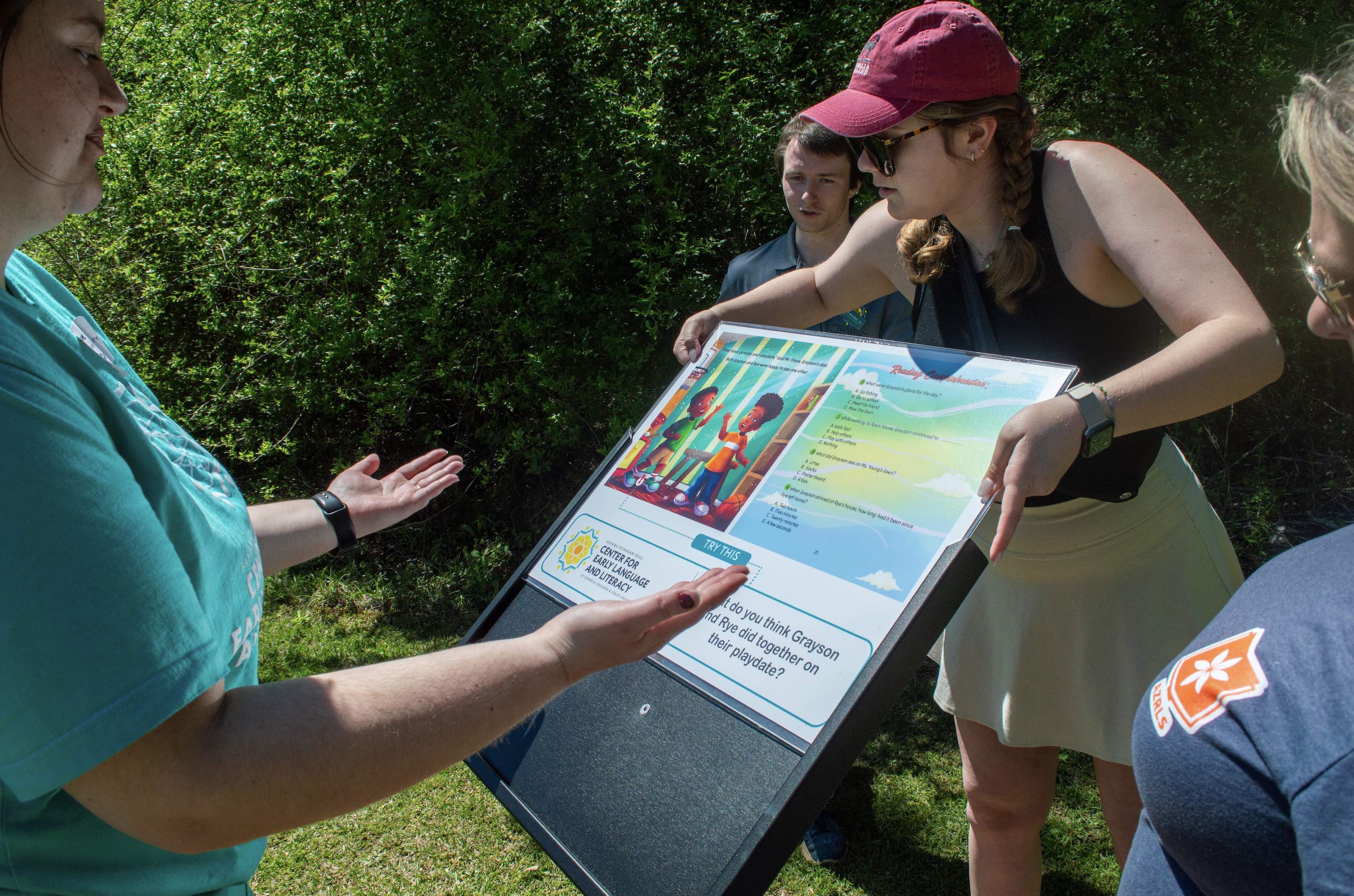 Volunteers slide a page of "Grayson's Play Date" into a storyboard frame at Tale Trail.