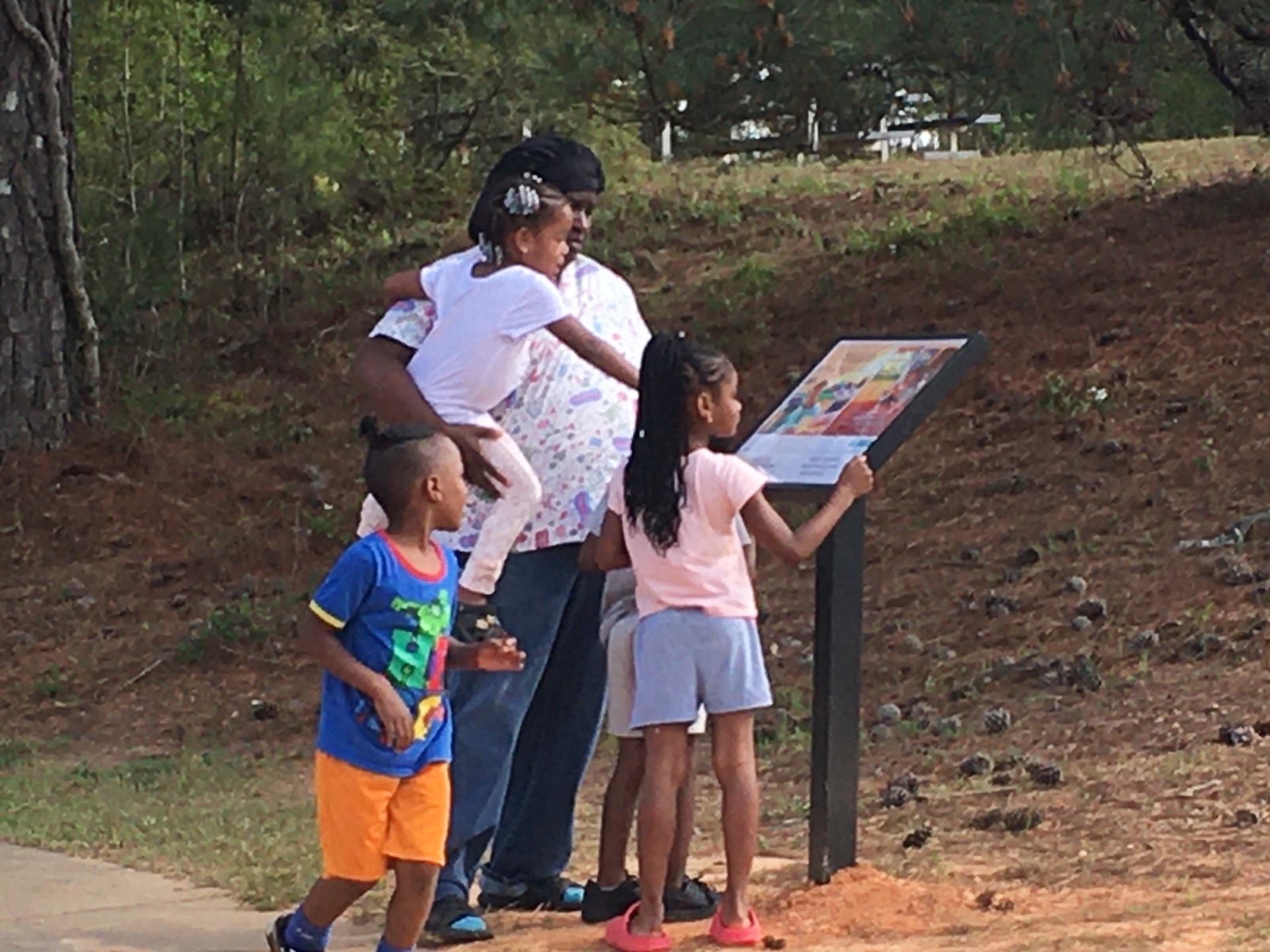 A family stops to read "Grayson's Play Date" at Tale Trail on a path at the Collins P. Lee Community Center in Milledgeville.