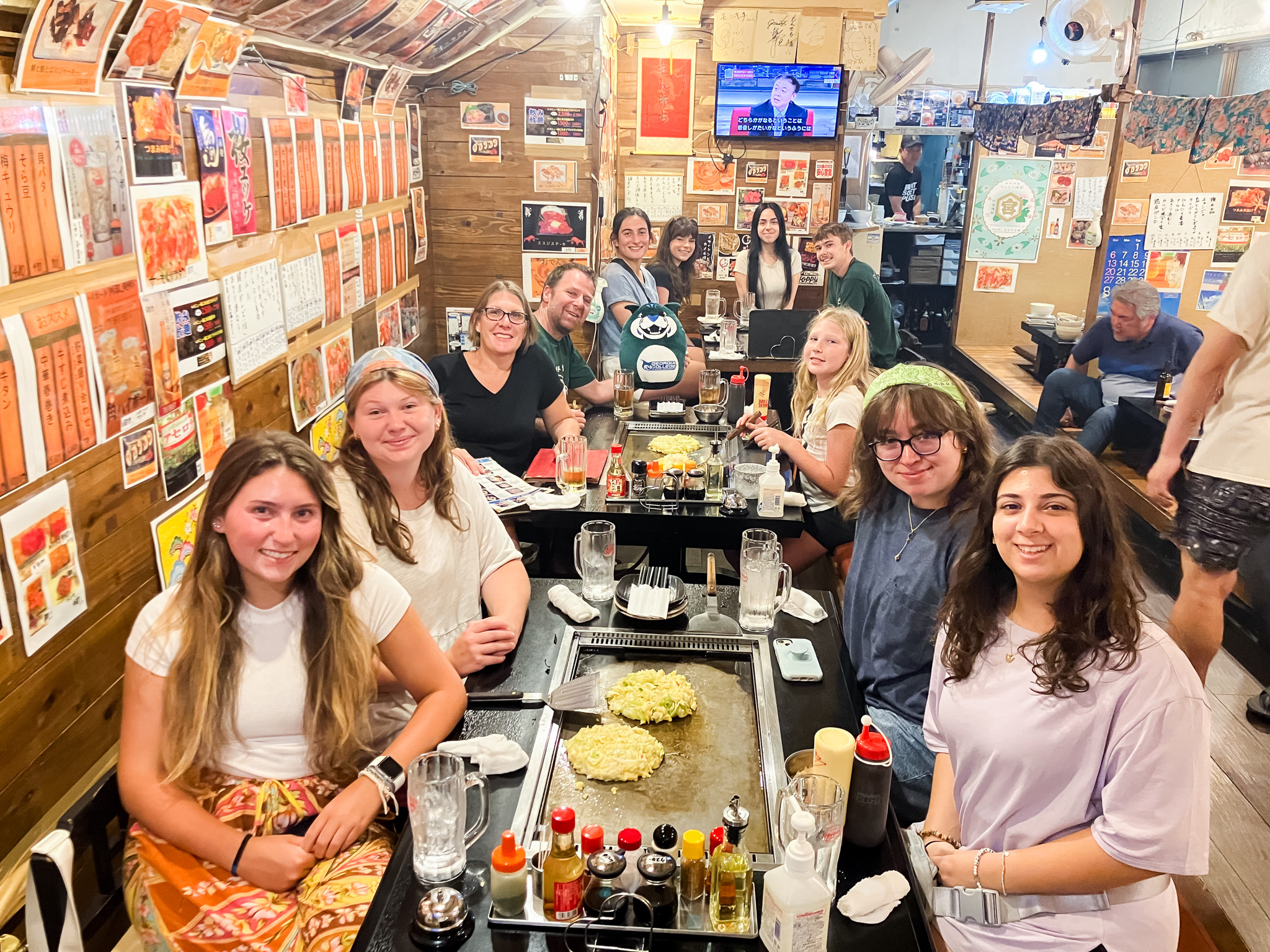 Students smile for a group photo around a long table laden with food.