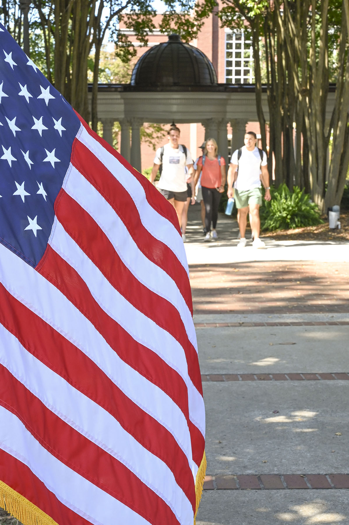 American flag in the foreground in front of the pergola on front campus