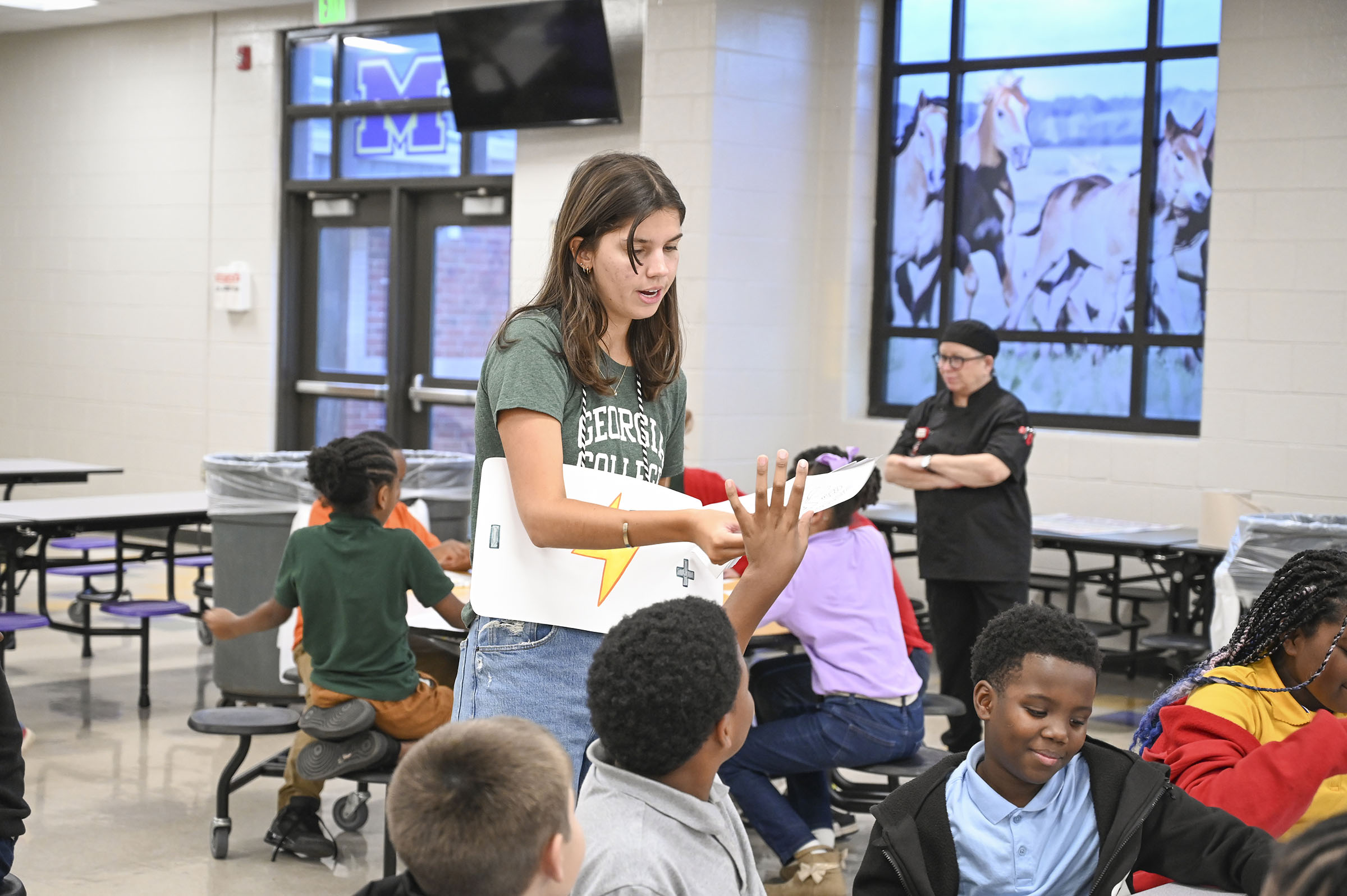 Capstone student Aiden McGowan passes out battery coloring sheets during the 'Battery Hero' challenge kickoff on Nov. 3 at Midway Hills Academy. (Photo: Anna Gay Leavitt)
