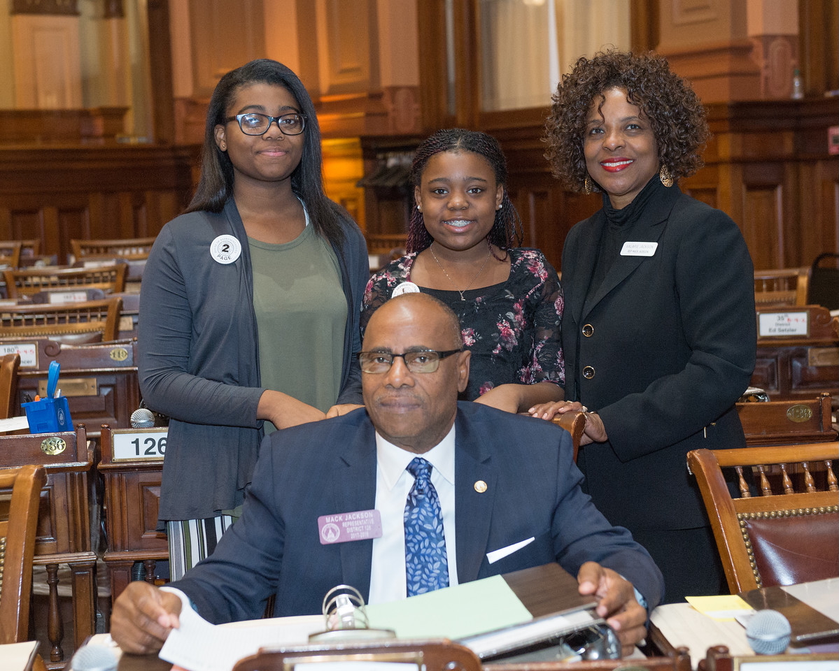Rep. Mack Jackson is seated in the General Assembly with his granddaughters who are his pages (L-R) Ke’Ambrya and Serenity and wife, Valerie.
