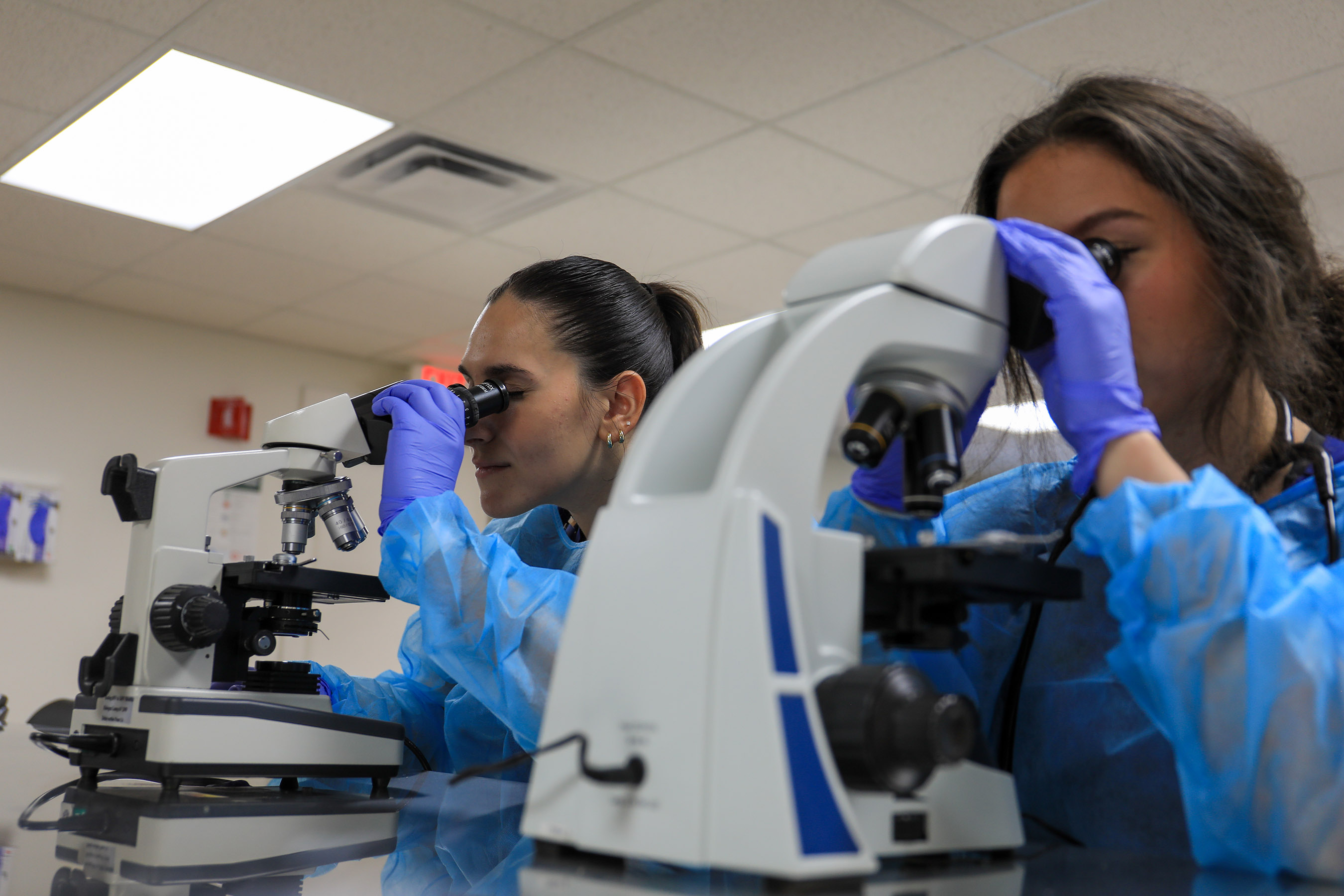 Students looking into microscopes in the wet lab of the GCSU Nursing SIM Center