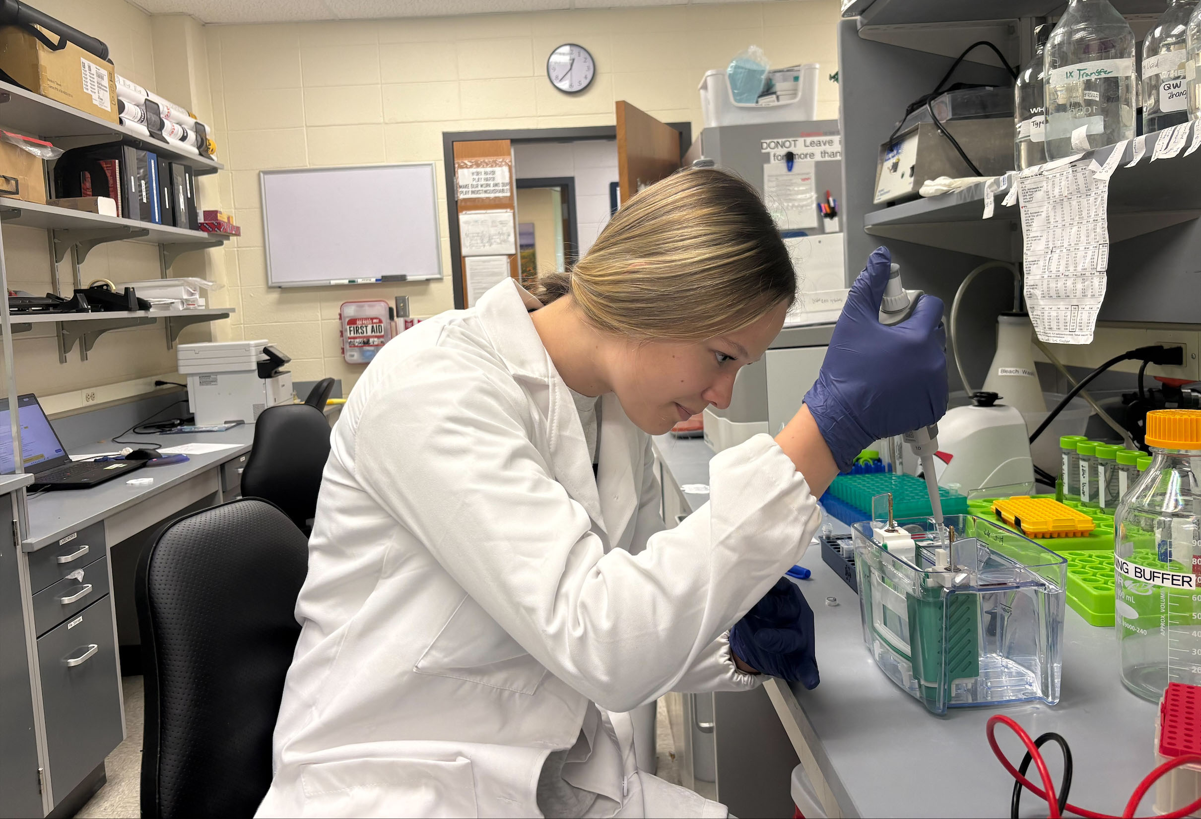 Rebecca DeRoth in the lab holding a pipette