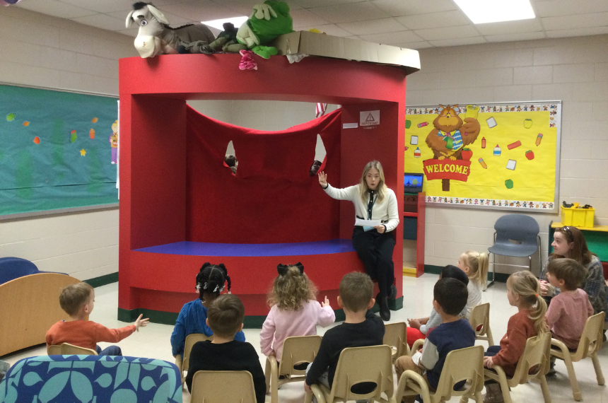 Children at the Montessori Academy watching a puppet show lesson on emotions.